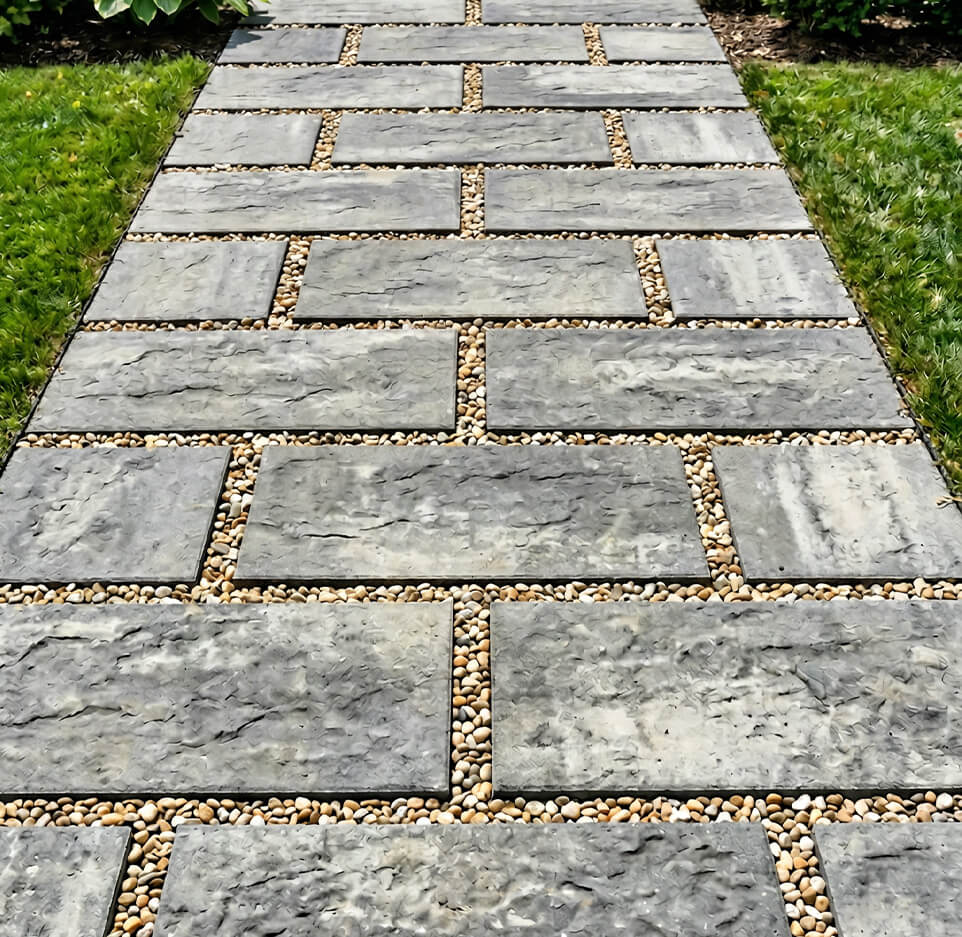 Paved stone pathway with small stones between tiles, leading through grass.