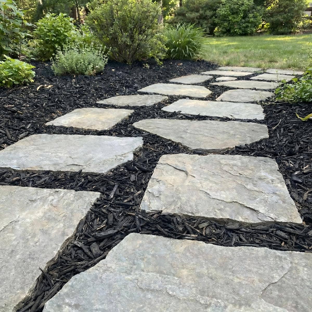 Black mulch securely bonded between live edge pavers with Shabebe Mulch Glue, helping the garden pathway stay neat through everyday foot traffic, pets, wind, and rain.